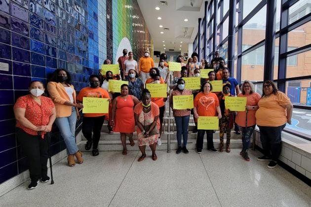 A group of staff members pose together wearing orange
