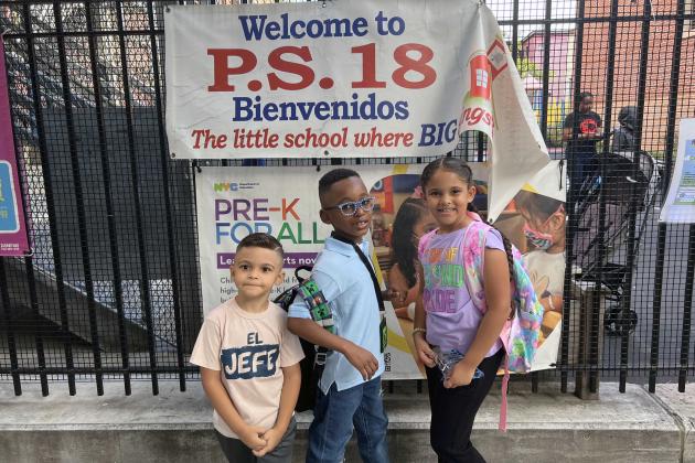 Three young students stand outside a school