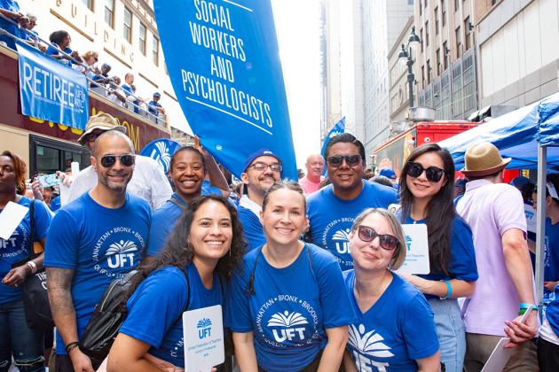 A group of parade goers pose for a photo all wearing blue