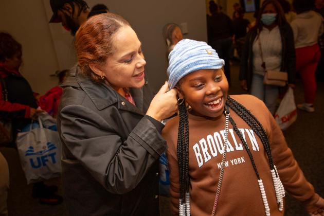 A woman helps a student with a new hat 