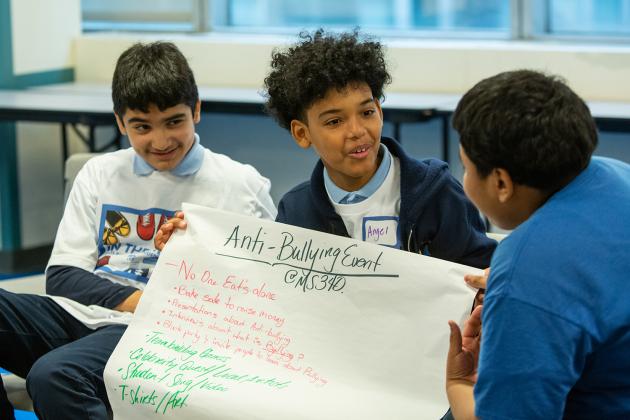 A student holds a poster reading "Anti-Bullying event"