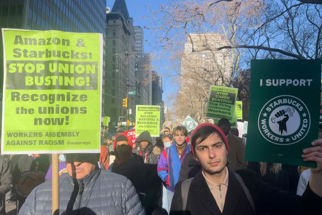 A group of people hold up signs at a Starbucks rally