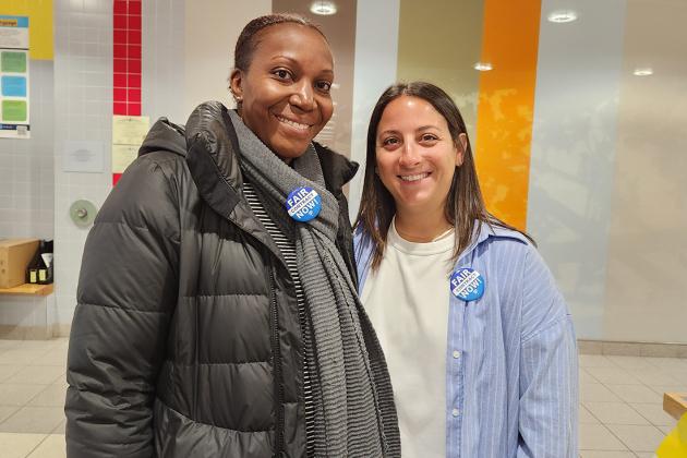 Two women pose for a photo wearing fair contract buttons 