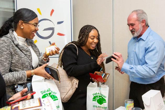 A man on the right shows women on the left something on his phone