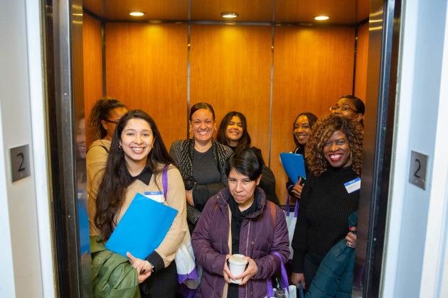 A group of members pose for a photo while in an elevator