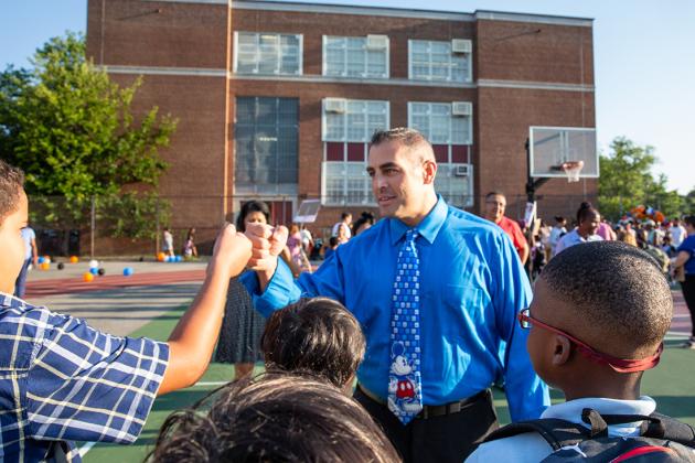 A teacher fist bumps with one of his students 