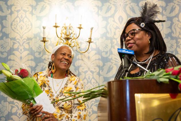 A woman on the left receives flowers from the woman on the right