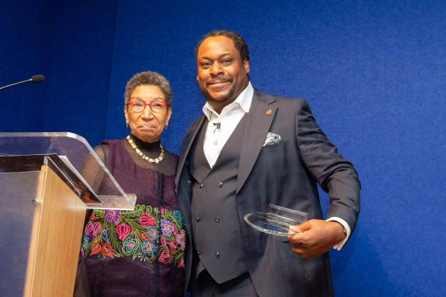A woman on the left and man on the right pose for a photo at the podium. 