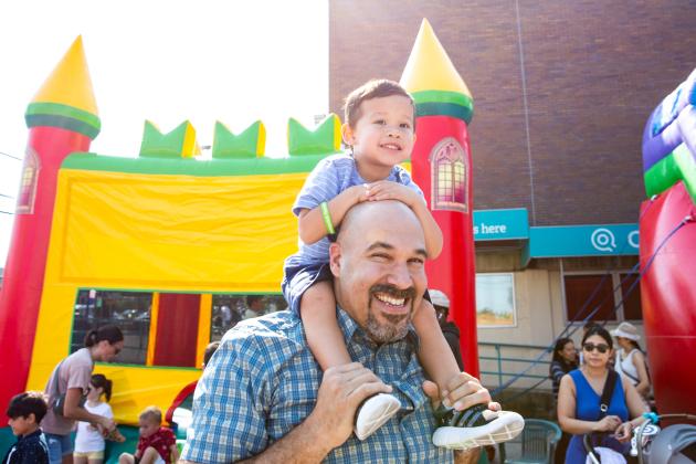 A father and his son smile outside near a bouncy house during a day of wellness for educators on September 14, 2024. 
