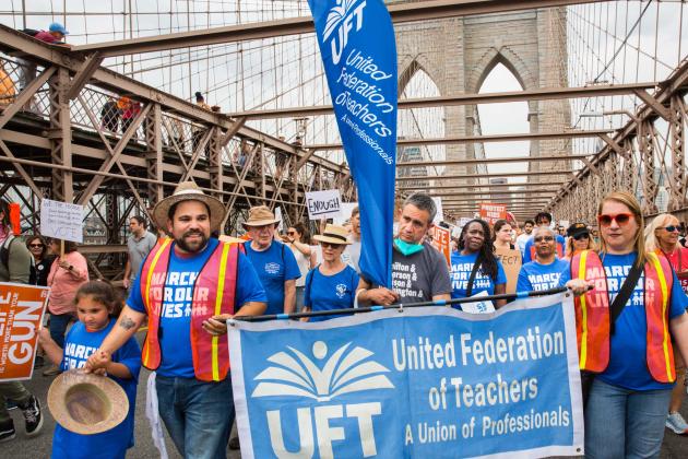 A group of men, women and children march over the Brooklyn Bridge with signs