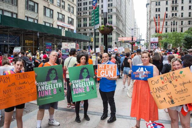 A group of protestors hold up signs in honor of Angellyh Yambo