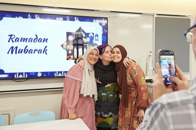 A man takes a photo of three women embracing at the 2024 UFT Muslim Educators Committee Ifar Dinner