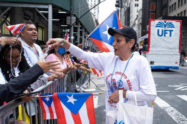 A woman hands out parade swag to parade attendees. 