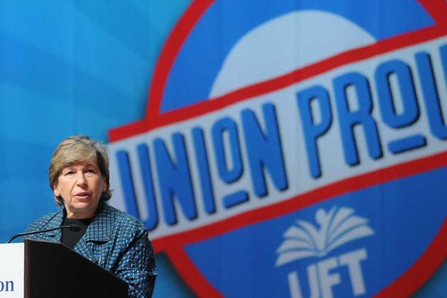 A woman speaks at a podium with a large "union proud" graphic in the background