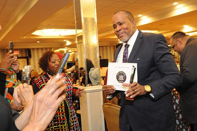 A man holds up his award while someone takes a photo of him