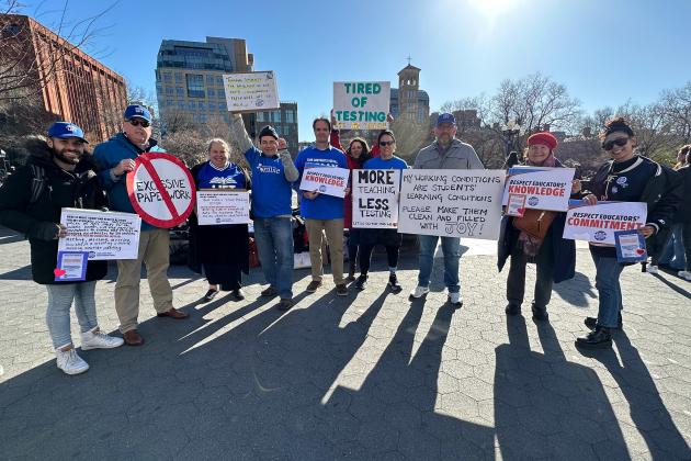 A group of members pose for a photo while holding signs 