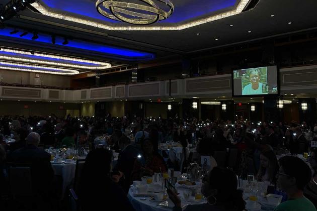 Attendees illuminate the flashlights on their phones to honor Ethan Holder (on screen) during the presentation of an AFT Special Recognition Award to the late paraprofessional.