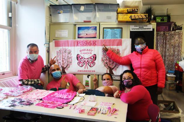 Group of members gathering and pointing to a sign for breast cancer awareness. 