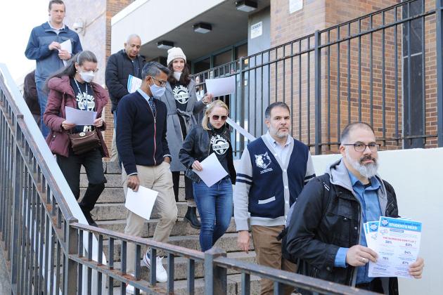 A group of staff members walk down the stairs outside of their school building