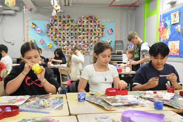 Two students sit at their desk and work on art projects in preparation for an art show at IS 34 on Staten Island.