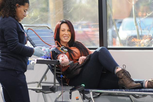 A woman smiles as she donates blood.
