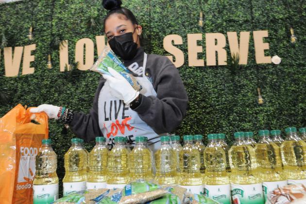 A woman wearing a mask packs food into grocery bags