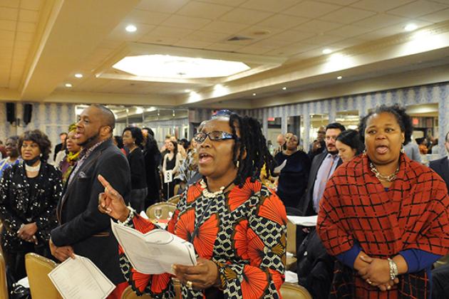 A crowd collectively sings at a celebration