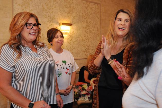 Three women smile while talking to one another 