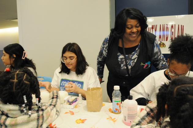 An older woman checks in on children working at a table