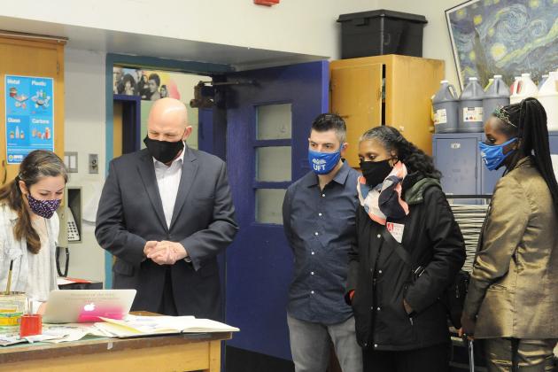 UFT President and staff gather around a table to view a laptop