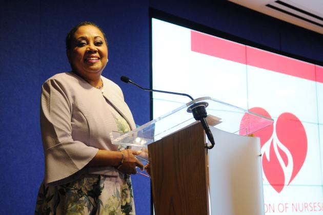 A woman at the podium smiles during a speech