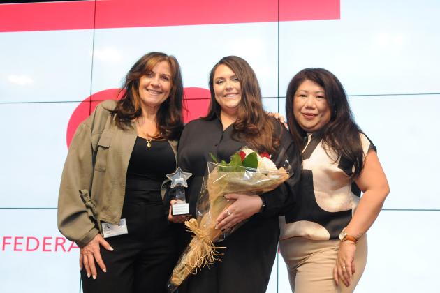 Three women pose for a photo on a stage 