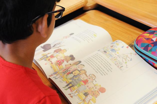 A student looks through a book in class. 