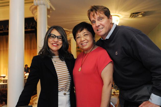 Two women and a man pose for a photo at a luncheon. 