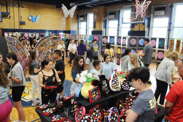 Attendees at the IS 34 art show on Staten Island walk through the gymnasium and look at the artwork made by students.