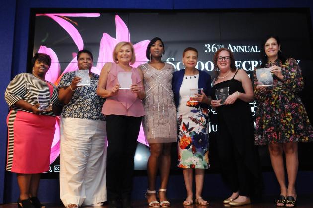 A group of award winners pose for a photo on the stage. 