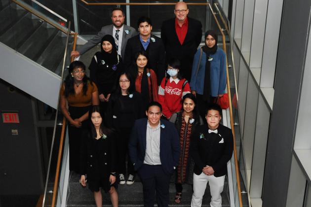 A group of award winners take a photo on the stairs. 