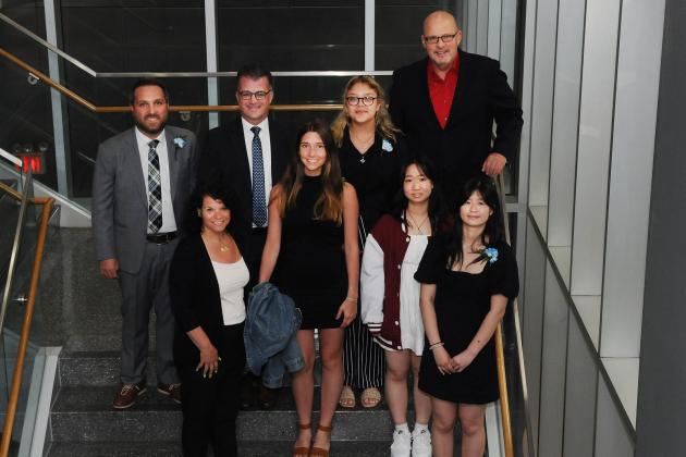 A group of award winners take a photo on the stairs. 