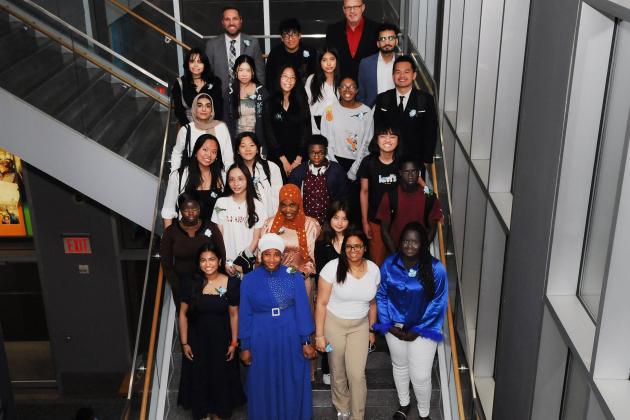 A group of award winners take a photo on the stairs. 