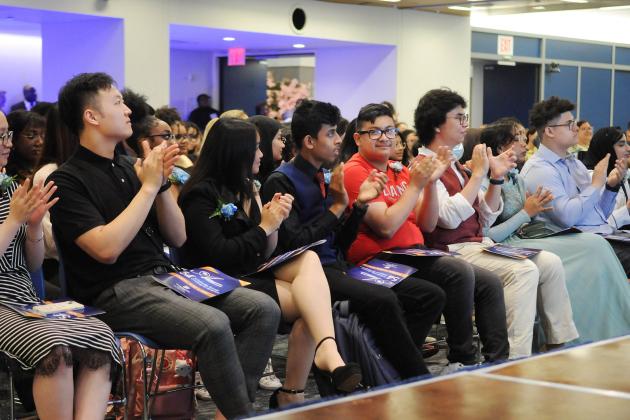 Attendees in the crowd applaud a speaker