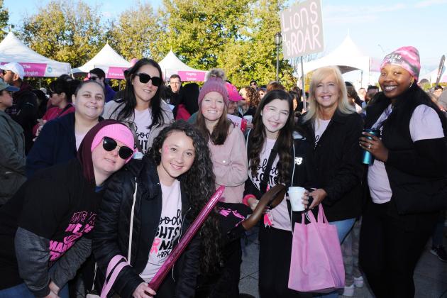 A group of marchers pose for a photo at a breast cancer awareness walk. 