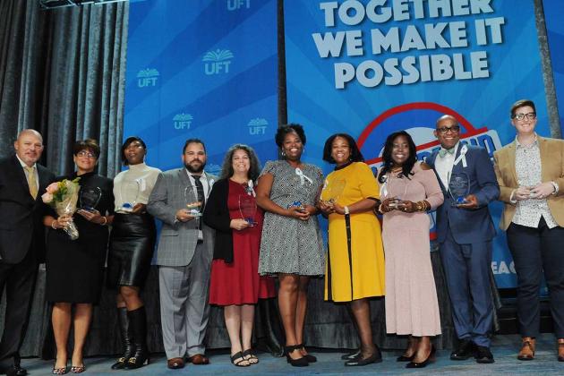 A group of award winners pose on stage for a photo. 