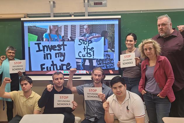 A group of teachers pose together in front of a smart board. 