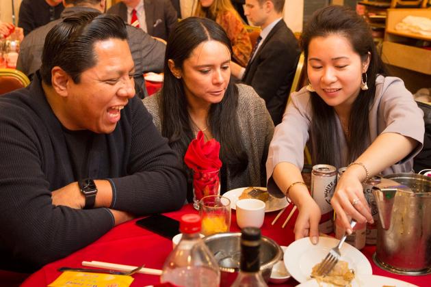Three people at a table are sharing food... and a laugh. 