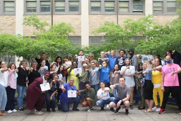 A group of staff members pose together outside of a school