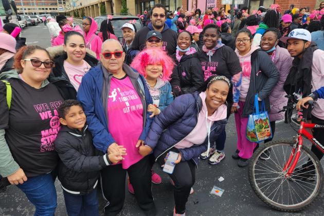 A large group of marchers pose for a photo and all of them are wearing pink attire.