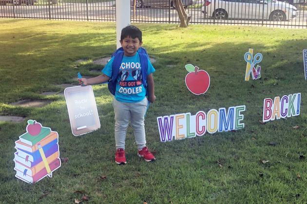A young students stands outside a school