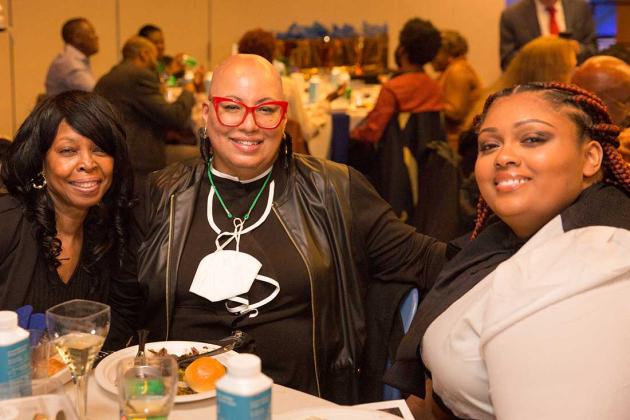 Three women pose for a photo at a table. 
