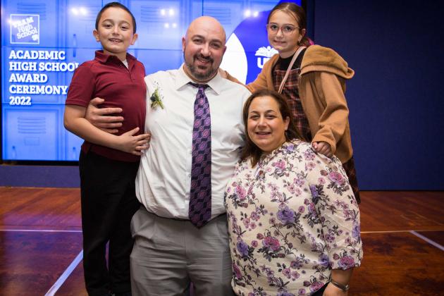 A man poses at the stage with his wife and children