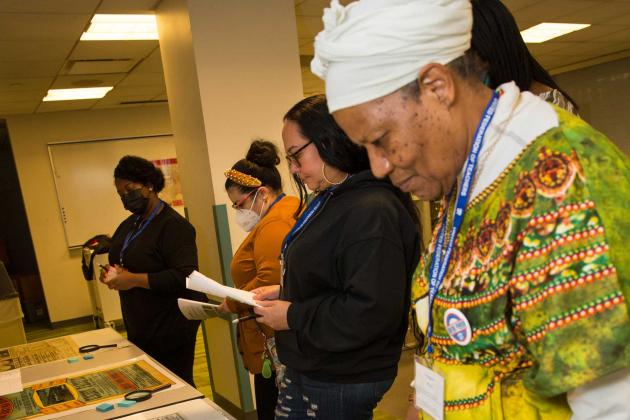 A woman stands by a table and looks at materials presented